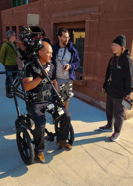 Paul O'Connor sits on a rickshaw dolly holding a steadicam setup.